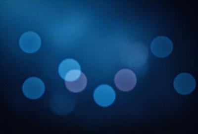 The primary subject of the image is a blue background with a pattern of white lights. The setting appears to be a dark room, and the visual style is a combination of a photo and digital art. The dominant colors are blue and white, creating a calm and serene atmosphere.