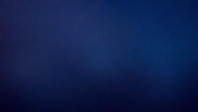 The primary subject of the image is the night sky, which is depicted in a dark blue hue. The setting is a vast, open space with no visible landmarks or objects. The visual style of the image is a photo, capturing the beauty of the night sky. The colors and mood of the image are serene and peaceful, as the night sky is often associated with tranquility and reflection.