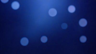 The primary subject of the image is a blue background with a pattern of white dots. The setting appears to be a dark room, and the visual style is a digital art or illustration. The dominant colors are blue and white, creating a calm and serene atmosphere.