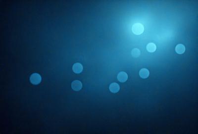 The primary subject of the image is a blue background with a pattern of white circles. The setting appears to be a dark room, and the visual style is a combination of a photo and digital art. The dominant colors are blue and white, creating a calm and serene atmosphere.