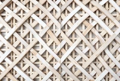 The primary subject of the image is a wooden lattice wall, which is the main object, scene, or focus of the image. The setting/background features a white wall, which serves as the environment, backdrop, or surface visible in the image. The visual style of the image is a photo, as it captures the wooden lattice wall in detail. The colors and mood of the image are predominantly white, giving it a clean and minimalist appearance.