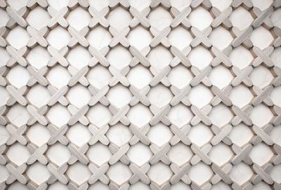 The primary subject of the image is a white marble wall with a pattern of holes or openings. The setting is a room with a white marble wall, and the visual style appears to be a photo of the wall. The dominant colors are white and grey, creating a clean and minimalist atmosphere.