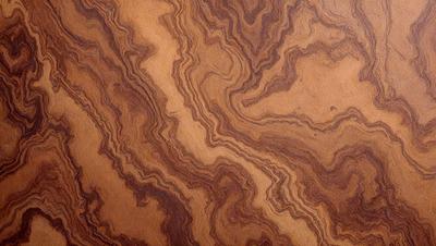 The primary subject of the image is a wooden table with a unique and intricate pattern on its surface. The table appears to be made of wood and has a distinctive design, possibly resembling a tree or a swirling pattern. The setting is indoors, with the table being the main focus of the scene. The visual style of the image is a close-up of the wooden table, showcasing its intricate design. The colors and mood of the image are warm and inviting, with the wooden table serving