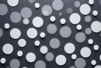 The primary subject of the image is a pattern of white circles on a gray background. The circles are arranged in various sizes and shapes, creating a visually interesting and unique design. The setting appears to be a black surface, which contrasts with the white circles, making them stand out even more. The visual style of the image is a combination of digital art and illustration, as it showcases a creative and artistic approach to design. The overall atmosphere of the image is calm and serene, with the white circles providing a sense of