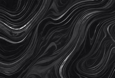 The primary subject of the image is a black and white patterned surface, which appears to be a marble or stone texture. The setting is a dark background, which contrasts with the patterned surface. The visual style is a close-up of the pattern, showcasing the intricate details of the design. The colors and mood of the image are predominantly dark, with the black and white pattern creating a sense of depth and complexity.
