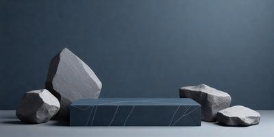 The primary subject of the image is a large, square, black stone. The setting is a gray wall, and the visual style is a photo. The colors and mood of the image are predominantly dark and moody, with the black stone as the focal point.