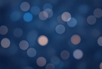 The primary subject of the image is a blue background with a pattern of bright, white, and orange lights. The visual style appears to be a digital art or illustration, as the lights are arranged in a visually appealing manner. The colors and mood of the image are vibrant and lively, with the bright lights creating a sense of energy and movement.