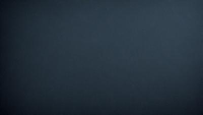 The primary subject of the image is a dark blue sky. The setting is a vast, open space with no visible landmarks or objects. The visual style is a simple, monochromatic image with no additional elements or textures. The colors and mood of the image are predominantly dark and moody, creating a sense of depth and vastness.