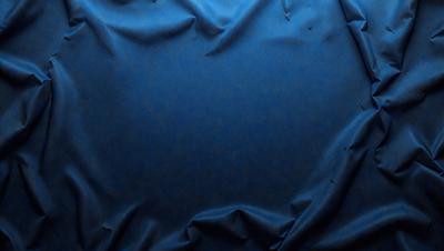 The primary subject of the image is a blue cloth, which is the main object, scene, or focus of the image. The setting or background of the image is a dark blue surface, which provides a contrasting backdrop for the cloth. The visual style of the image is a photo, as it captures the cloth in a realistic manner. The dominant colors in the image are blue, which creates a calm and serene atmosphere.