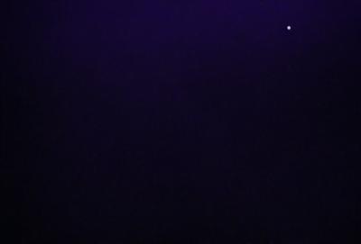 The image is a black and white photo of a dark, starry night sky. The primary subject is the vast expanse of the night sky, with no visible objects or landmarks. The setting is a nighttime scene with a few stars visible in the sky. The visual style is a traditional black and white photo, which adds a sense of nostalgia and timelessness to the image. The colors and mood are predominantly dark and moody, with the stars providing a touch of brightness and contrast.
