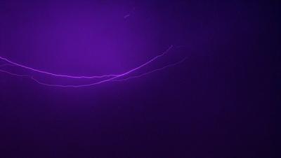 The primary subject of the image is a purple lightning bolt, which is the main object, scene, or focus of the image. The setting/background is a dark purple sky, and the visual style is a photo. The colors and mood of the image are dominated by the purple lightning bolt, creating a dramatic and intense atmosphere.