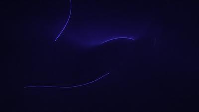 The primary subject of the image is a blue background with a purple light streaking through it. The setting appears to be a dark room, and the visual style is a combination of digital art and illustration. The colors and mood of the image are predominantly dark and moody, with the purple light adding a touch of brightness to the scene.