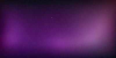 The primary subject of the image is a single star, which is located in the middle of the purple sky. The setting is a dark, purple background, which creates a dramatic and moody atmosphere. The visual style of the image is a photo, capturing the star and its surroundings. The colors and mood of the image are predominantly purple, with the star being the only bright spot in the sky.