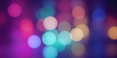 The primary subject of the image is a colorful, blurry background featuring a mix of green, yellow, and orange colors. The setting appears to be a nighttime scene with a brightly lit environment. The visual style of the image is a combination of a photo and digital art, creating a unique and vibrant atmosphere. The colors and mood of the image are lively and energetic, with the green, yellow, and orange hues creating a sense of warmth and excitement.