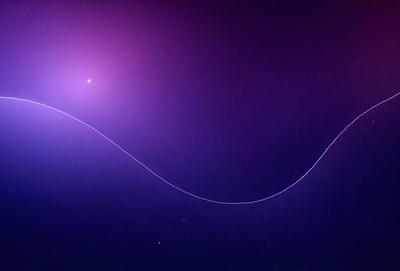 The primary subject of the image is a long, curved line that appears to be a wire or a rope. The line is stretched across the entire image, creating a sense of depth and dimension. The setting is a dark, purple background that contrasts with the line, making it stand out. The visual style of the image is a combination of a photo and a digital art, as it captures the essence of a wire or rope while maintaining a sense of depth and dimension. The colors and mood of the