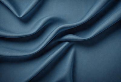 The primary subject of the image is a blue fabric, possibly a piece of cloth or a curtain. The setting is a room with a blue background, which creates a cohesive and visually appealing environment. The visual style of the image is a close-up of the blue fabric, showcasing its texture and details. The colors and mood of the image are predominantly blue, giving it a calm and serene atmosphere.