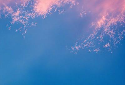 The primary subject of the image is the sky, which is a deep shade of blue. The setting is a cloudy day, with the clouds scattered across the sky. The visual style of the image is a photo, capturing the beauty of the cloudy sky. The colors and mood of the image are serene and peaceful, as the clouds float gently in the sky.