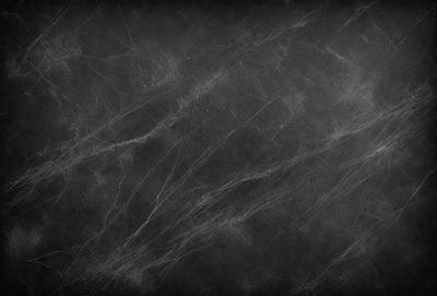 The primary subject of the image is a blackboard with a white chalkboard surface. The setting is a classroom or a similar environment where chalkboards are commonly used. The visual style is a close-up of the chalkboard, showcasing the texture and pattern of the surface. The dominant colors are black and white, creating a clean and minimalist atmosphere.