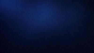 The primary subject of the image is a dark blue sky with no clouds. The setting is a vast, open space with no visible landmarks or objects. The visual style is a simple, unadorned representation of the sky. The colors and mood are predominantly dark and moody, with the blue sky serving as the main focal point.