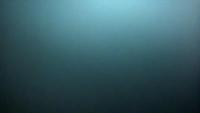 The primary subject of the image is a large, dark blue sky. The setting is a vast, open space with no visible landmarks or objects. The visual style is a photo, capturing the expansive view of the sky. The colors and mood are predominantly dark and moody, with the blue sky serving as the main focal point.