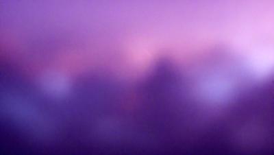 The primary subject of the image is a purple sky with clouds. The setting is a cloudy sky, and the visual style appears to be a photo. The colors and mood of the image are predominantly purple, creating a serene and calming atmosphere.