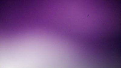 The image features a purple wall with a single dot in the upper right corner. The purple wall serves as the primary subject, creating a unique and visually striking scene. The setting is indoors, with the wall being the main focus of the image. The visual style appears to be a photo, capturing the purple wall and the dot in detail. The colors and mood of the image are predominantly purple, giving it a calm and serene atmosphere.