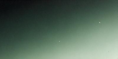 The primary subject of the image is the moon, which is seen in the sky. The setting is a dark, cloudy night sky, with the moon being the main focus. The visual style is a photo, capturing the moon in its natural environment. The colors and mood of the image are predominantly dark and moody, with the moon being the only light source in the scene.