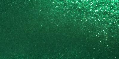 The primary subject of the image is a green background with a pattern of glittering stars. The setting appears to be a dark room, and the visual style is a close-up of the green background. The colors and mood of the image are predominantly dark and moody, with the green background and glittering stars adding a touch of brightness and interest.