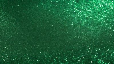 The primary subject of the image is a close-up of a green glittery surface, which appears to be a wall or a piece of fabric. The setting is indoors, with the green glittery surface being the main focus of the image. The visual style is a close-up, which emphasizes the glittery texture of the surface. The colors and mood of the image are predominantly green, with the glittery surface adding a sense of sparkle and shine to the overall atmosphere.
