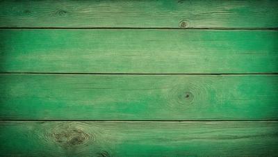 The primary subject of the image is a green wooden surface, which appears to be a wooden plank or a piece of wood. The setting is a green background, which complements the green wooden surface. The visual style of the image is a close-up of the wooden surface, showcasing its texture and details. The colors and mood of the image are predominantly green, creating a calm and natural atmosphere.
