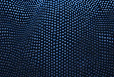The primary subject of the image is a close-up of a blue, textured surface with a pattern of black dots. The setting appears to be a dark room, and the visual style is a combination of a photo and a digital artwork. The dominant colors are blue and black, creating a moody atmosphere.