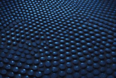 The primary subject of the image is a blue surface with a pattern of blue circles. The setting appears to be a dark room, and the visual style is a close-up of the blue surface. The dominant colors are blue, and the overall atmosphere is calm and serene.