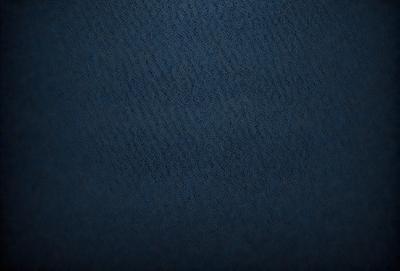 The primary subject of the image is a blue fabric with a pattern of waves. The setting is a dark background, which contrasts with the blue fabric. The visual style is a close-up of the fabric, showcasing its texture and pattern. The colors and mood of the image are predominantly dark and moody, with the blue fabric serving as the focal point.
