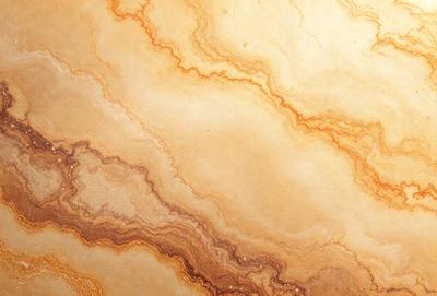 The image features a marble-like surface with a yellowish hue. The primary subject is a pattern of swirls and waves, which gives the surface a unique and intricate appearance. The setting is a natural environment, possibly a stone or marble wall, with the background being the marble-like surface itself. The visual style is a combination of natural and artistic elements, creating a visually appealing and textured surface. The colors and mood of the image are warm and earthy, with the yellowish hue