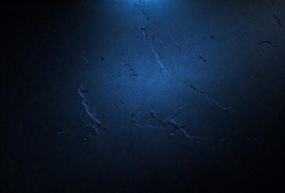 The primary subject of the image is a black countertop with a blue tint. The setting is a dark room, and the visual style appears to be a photo. The countertop has a blue tint, and the overall atmosphere is dark and moody.