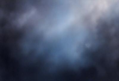 The primary subject of the image is a cloudy sky. The setting is a dark, cloudy day with a blue hue. The visual style is a photo of the sky, showcasing the clouds and their varying shades of blue. The colors and mood of the image are predominantly dark and moody, with the clouds creating a dramatic backdrop.