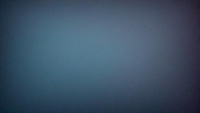 The primary subject of the image is a large, empty, and dark blue sky. The setting is a vast, open space with no visible landmarks or objects. The visual style is a black and white photo, which adds a sense of depth and contrast to the scene. The colors and mood of the image are predominantly dark and moody, with the blue sky serving as the main focal point.