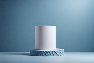 The primary subject of the image is a white cake, which is placed on a blue table. The cake is positioned in the center of the table, and it appears to be the main focus of the scene. The setting is a simple, clean environment, with the cake being the only object in the frame. The visual style of the image is a close-up shot of the cake, highlighting its texture and details. The colors in the image are predominantly blue, which gives the scene a calm and soothing
