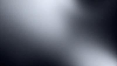 The primary subject of the image is a white light source, which appears to be a light bulb or a bright spot in the darkness. The setting is a black background, which contrasts with the white light source. The visual style is a close-up of the light source, emphasizing its brightness and intensity. The colors and mood of the image are predominantly dark, with the white light source being the only source of brightness and contrast.