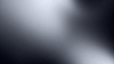 The primary subject of the image is a white light source, which appears to be a light bulb or a bright spot in the darkness. The setting is a black background, which contrasts with the white light source. The visual style is a close-up of the light source, emphasizing its brightness and intensity. The colors and mood of the image are predominantly dark, with the white light source being the only source of brightness and contrast.