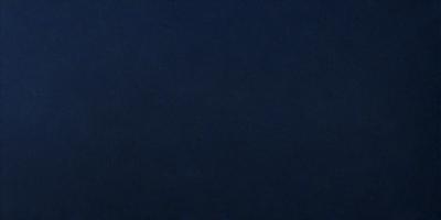 The primary subject of the image is a large, dark blue surface. The setting is a vast, open space with no visible objects or people. The visual style is a close-up of the dark blue surface, which gives the image a moody and dramatic atmosphere.