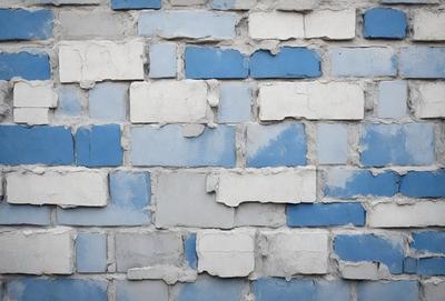 The primary subject of the image is a blue brick wall with a few missing bricks. The setting is a brick wall, and the visual style is a photo. The colors and mood of the image are predominantly blue, giving it a calm and serene atmosphere.