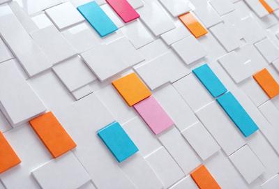 The primary subject of the image is a white tile wall with a pattern of colored squares. The setting is a white tile wall, and the visual style is a pattern of colored squares. The dominant colors are white, pink, orange, and blue, creating a vibrant and lively atmosphere.