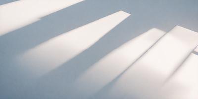 The primary subject of the image is a white wall with sunlight shining on it. The setting is a room with a white background. The visual style is a photo of the sunlight on the wall. The colors and mood are predominantly white, creating a clean and bright atmosphere.