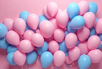 The primary subject of the image is a large pile of balloons, predominantly pink and blue. The balloons are arranged in a visually appealing manner, creating a sense of celebration or festivity. The setting is a pink background, which adds to the overall mood of the image. The visual style is a close-up of the balloons, showcasing their vibrant colors and textures. The colors and mood of the image are predominantly cheerful and joyful