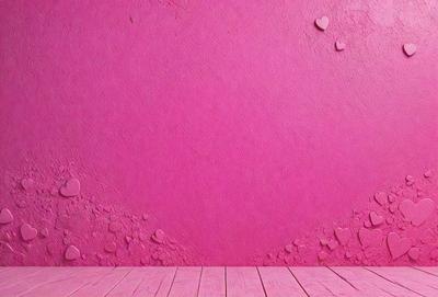 The primary subject of the image is a pink wall with a heart-shaped pattern on it. The setting is a room with a wooden floor. The visual style is a photo, and the dominant colors are pink and red, creating a warm and inviting atmosphere.