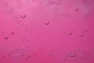 The primary subject of the image is a pink wall with hearts painted on it. The hearts are scattered across the wall, creating a visually appealing and playful design. The setting is a room with a pink background, which complements the hearts' color. The visual style is a painting, giving the image a unique and artistic touch. The colors and mood of the image are predominantly pink, which evokes a sense of warmth, love, and happiness.