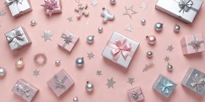 The primary subject of the image is a pink background with various presents and ornaments scattered across it. The setting is a pink surface, and the visual style appears to be a combination of photo and digital art. The colors and mood of the image are predominantly pink, creating a warm and festive atmosphere.