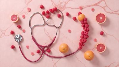 The primary subject of the image is a purple stethoscope, which is placed on a pink marble surface. The setting is a pink background, and the visual style appears to be a photo. The colors and mood of the image are predominantly pink and warm, creating a pleasant and inviting atmosphere.