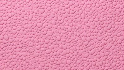 The primary subject of the image is a pink surface with a pattern of small circles. The setting is a close-up of the pink surface, which appears to be a wall or a piece of fabric. The visual style is a close-up of the pink surface, which gives a sense of depth and texture. The colors and mood of the image are predominantly pink, creating a warm and inviting atmosphere.